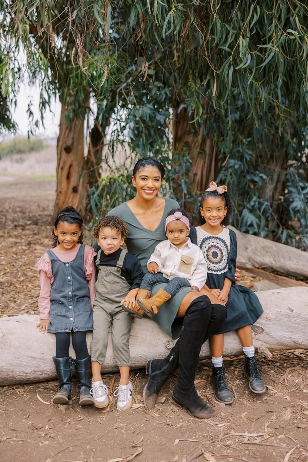 Family with three kids sitting on a log in a eucalyptus forest
